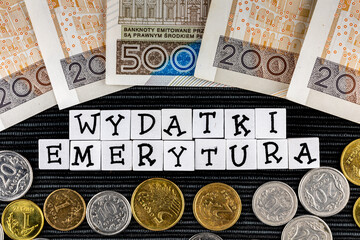 The wording "wydatki emerytury" translated as "expenses pensions" and many Polish coins and banknotes on the black background. New taxation rules in Poland. Pension versus expenses. 
