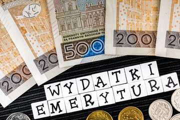 The wording "wydatki emerytury" translated as "expenses pensions" and many Polish coins and banknotes on the black background. New taxation rules in Poland. Pension versus expenses.