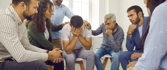 Comforting. Compassionate people put their hand on shoulder of man who cries during conversation in...