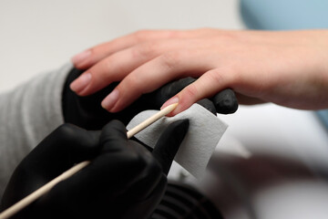Manicurist makes a hardware manicure to a client of a beauty salon. The master uses an orange stick to push back the cuticle. The concept of beauty and nail care.