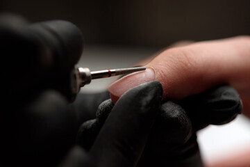 Manicurist makes a hardware manicure to a client of a beauty salon. The process of lifting the...
