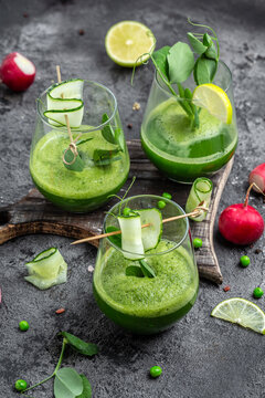 Refreshing kale cucumber green smoothie in a glass on concrete background. Detox smoothie, green fresh peas, cucumber, radish, spinach and lime. vertical image. top view