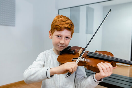 Smiling boy playing violin in music school