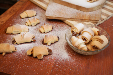 Fototapeta na wymiar Croissants with apple jam sprinkled with powdered sugar on a wooden background.