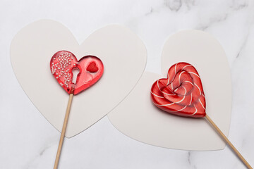 Two heart shaped lollipops on white marble background. Candy Love concept. Valentine's Day.