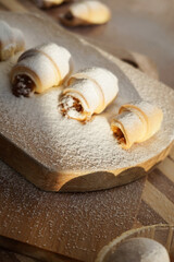 Fototapeta na wymiar Croissants with apple jam sprinkled with powdered sugar on a wooden background.
