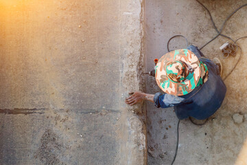 male worker is using a drilling tool to drill into a concrete road to reinforce the anchor before building a stable parallel concrete road. Male worker drilling concrete road with drilling machine