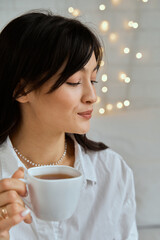 A young girl on the background of glowing LED lights with a cup of tea.