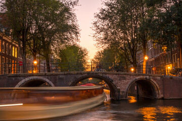 Sunset on the Amsterdam Canal and a Boat Under the Bridge