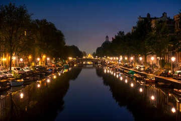 Fototapeta na wymiar Night Canal in Amsterdam With Parked Cars and Boats