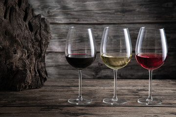 Red, white and rose wine in wine glasses on dark wood background. Beverage and wine concept.