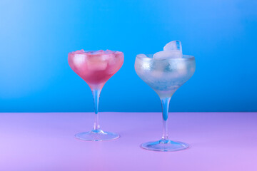 Cocktail glasses with colorful drink on blue and pink background. Summer cocktail party background.