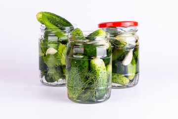 Pickled cucumbers in glass jar on white background.