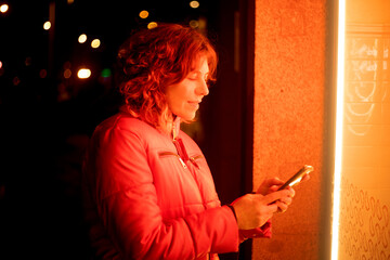 woman at night with lights using her cell phone