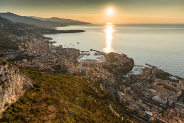 Aerial view of the Principality of Monaco at sunrise, Monte-Carlo, old town, view point in La Turbie at morning, port Hercule, Prince Palace, Mountains, Megayachts, a lot of boats, sun reflection