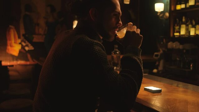 Portrait of a young guy in a night bar. A man drinks a cocktail and rests.