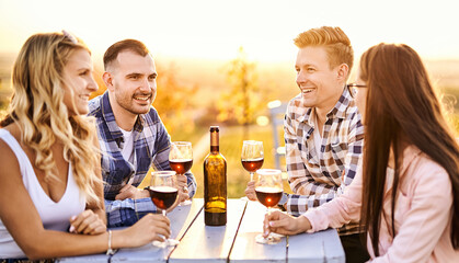 Young friends having fun outdoors - Happy people enjoying harvest time together at farmhouse winery countryside - Youth and friendship concept - Tasting red wine at vineyard before sunset