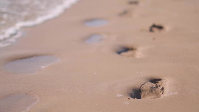Close up of Footsteps on sandy beach washing away by wave, Beach Background. Holiday concept, Background for summer holidays at beach.