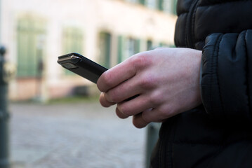 Closeup of smartphone in hand of young man standing in the street