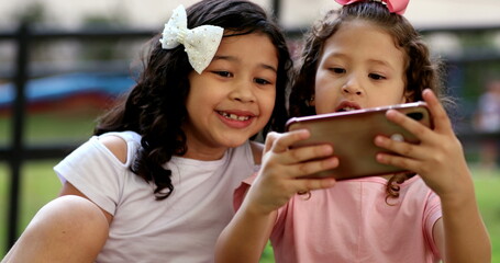 Excited little girls holding smartphone device outside