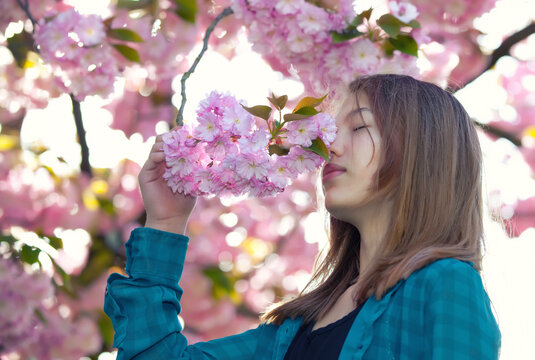 young girl smelling pink blossoms