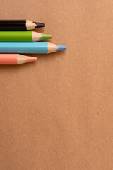 School, education and art concept with colorful pencils on natural recycled paper background.