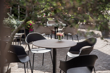Outdoor cafe area with black tables, armchairs and flowers