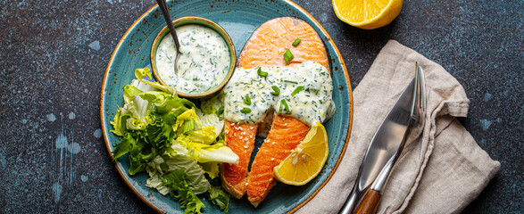 Healthy food meal cooked grilled salmon steaks with white dill sauce and salad leafs on plate on...