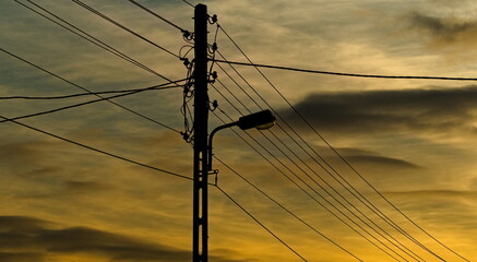 High voltage pole. Wires with electricity. Under Voltage. street lamp. pole on the background of sunset