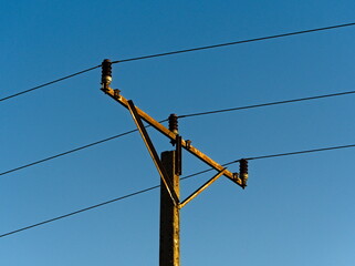 High voltage pole. An old, rusted pole with wires. Wires with electricity. Under Voltage