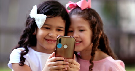 Children addicted to cellphone, two little girls looking at smartphone device on social media