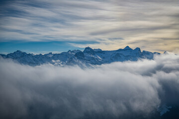 Fototapeta na wymiar Snowy mountains hiding behind the clouds as seen from Fronalpstock peak