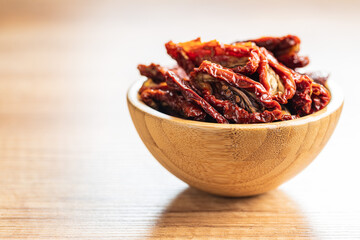 Sun dried tomatoes in bowl on wooden table.