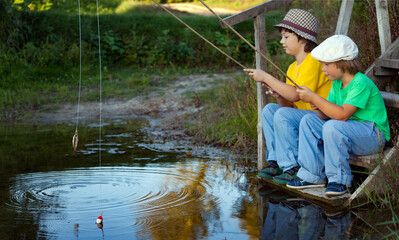 Happy boys go fishing on the river, Two children of the fisher with a fishing rod on the shore of lake