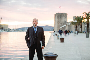 Geschäftsmann steht souverän auf Promenade am Meer