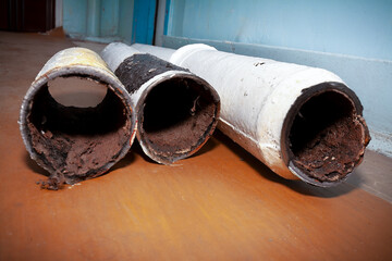 Three pieces of an old sewer pipe. Apartment in a multi-storey residential building in the city. Heavy pollution. Horizontal frame. Soft focus