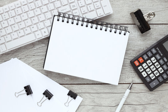 wooden office table with empty notebook, computer keyboard and other stationery. Top view with copy space.