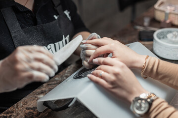 Female hands caring for nails, close-up. Woman does a manicure in a beauty salon. Professional saws a nail with a file