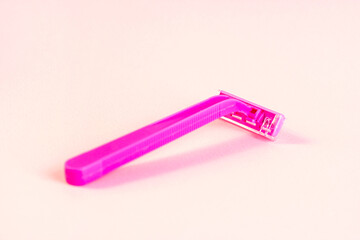 Pink disposable woman razor on light pastel background. Hair removing, epilation procedure and shaving concept.