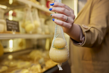 Delicious fresh Caciocavallo and Scamorza cheese hanging. Italian cheeses close up. The cheeses are...