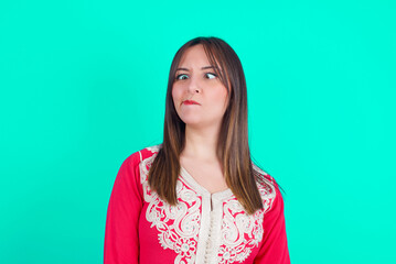 young beautiful moroccan woman wearing traditional caftan dress over green background making grimace and crazy face, screaming out of control, funny lunatic expressing freedom and wild.