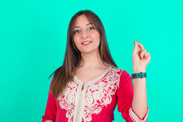 young beautiful moroccan woman wearing traditional caftan dress over green background pointing up with hand showing up seven fingers gesture in Chinese sign language QÄ«.