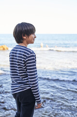 Fototapeta na wymiar The boy stands on a rock by the sea