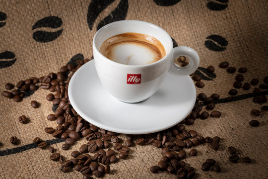 Cup of Illy coffee with milk on coffe beans