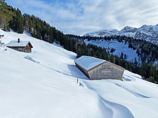 Idyllic Swiss alpine mountain huts dressed in winter clothes and in a fresh snow cover on slopes on the Alpstein mountain range - Mountain pass Schwägalp, Switzerland (Schweiz)