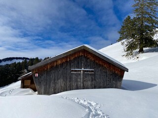 Idyllic Swiss alpine mountain huts dressed in winter clothes and in a fresh snow cover on slopes on the Alpstein mountain range - Mountain pass Schw&auml;galp, Switzerland (Schweiz)