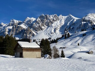 Idyllic Swiss alpine mountain huts dressed in winter clothes and in a fresh snow cover on slopes on the Alpstein mountain range - Mountain pass Schw&auml;galp, Switzerland (Schweiz)