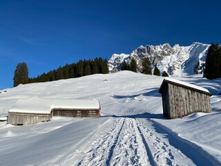 Idyllic Swiss alpine mountain huts dressed in winter clothes and in a fresh snow cover on slopes on the Alpstein mountain range - Mountain pass Schw&auml;galp, Switzerland (Schweiz)