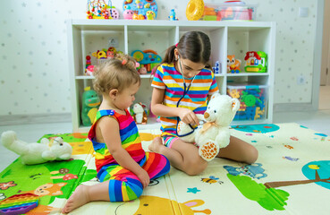 Fototapeta premium Children play together treat the bear. Selective focus.