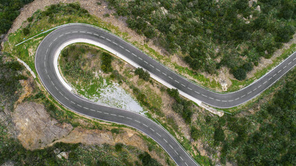 Empty long mountain road to the horizon on a sunny summer day at bright sunset - aerial drone shot
